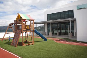 Área de juegos con deslizador y culumpios con pista de atletismo y grama artificial